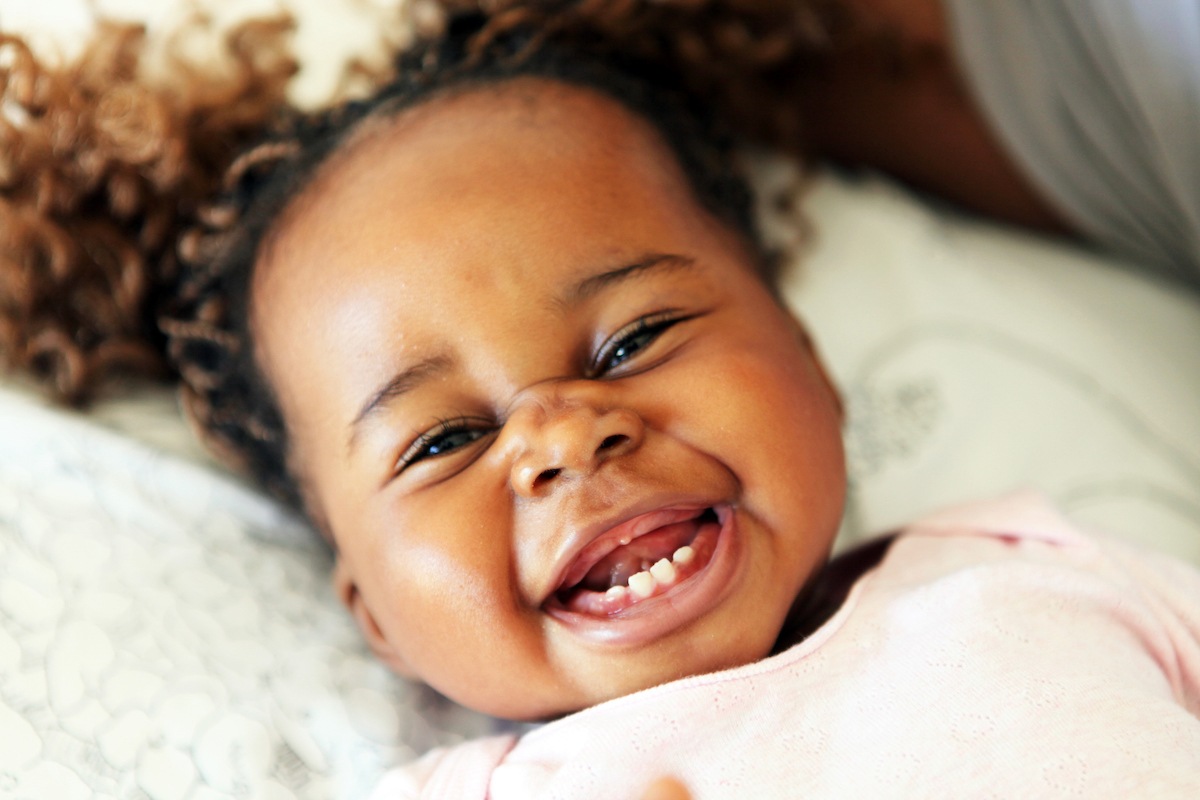 baby smiling with first bottom teeth growing in