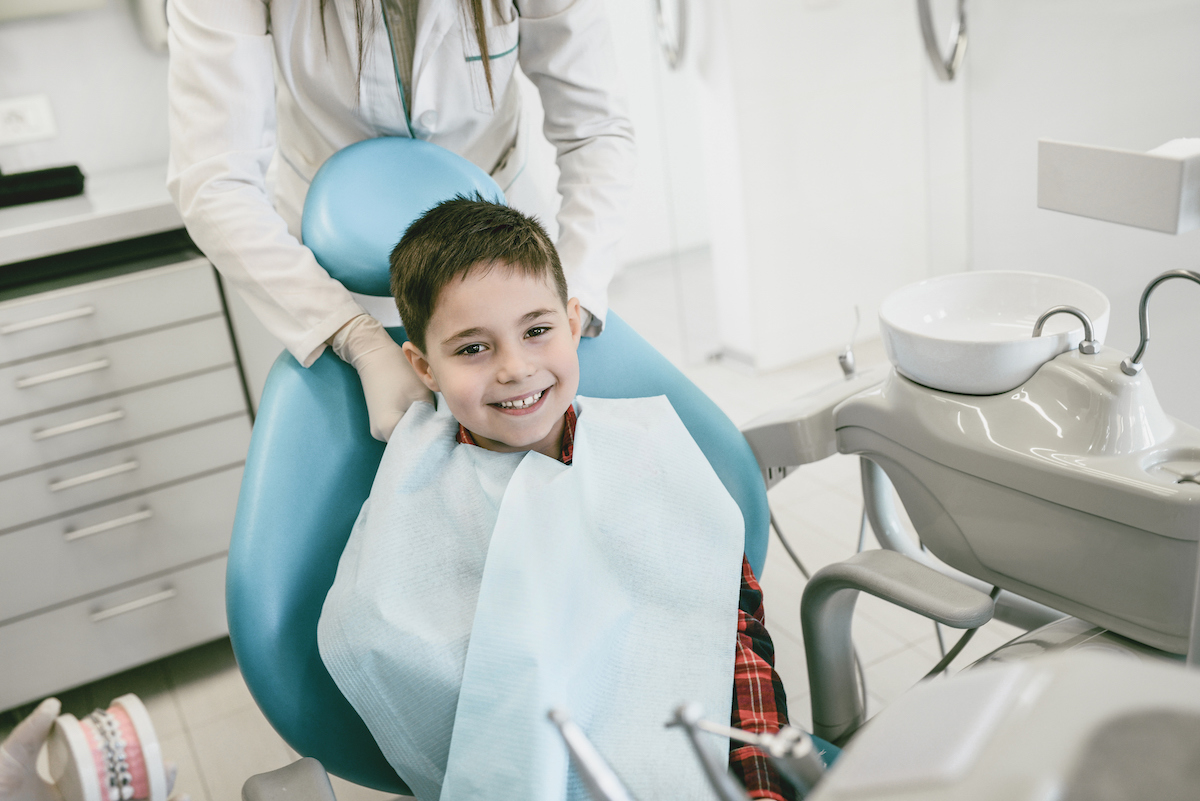 boy sitting in dentist chair and smiling