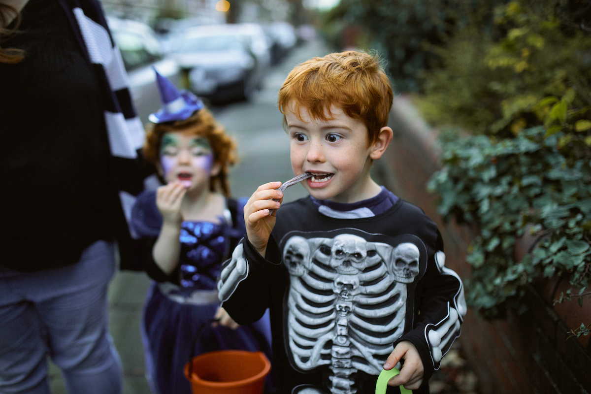 boy in a skeleton costume eating a piece of candy