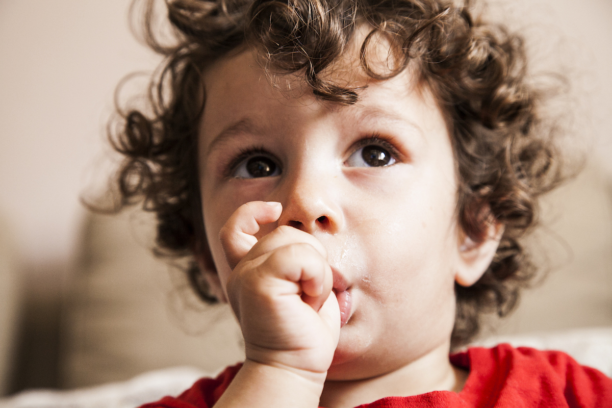 boy with curly hair sucking his thumb