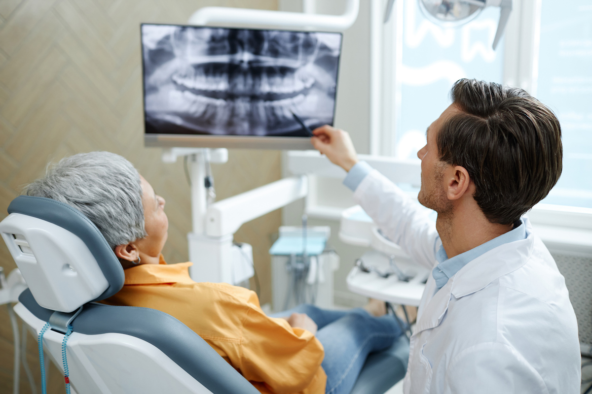 dentist showing patient their dental x-ray on TV screen